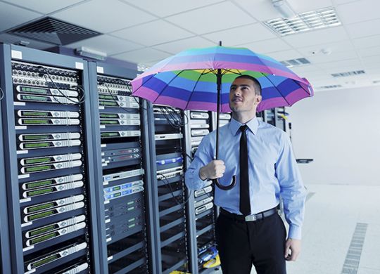 young handsome business man  engineer in .businessman hold  rainbow colored umbrella in server datacenter room  and representing security and antivirus sofware protection concept