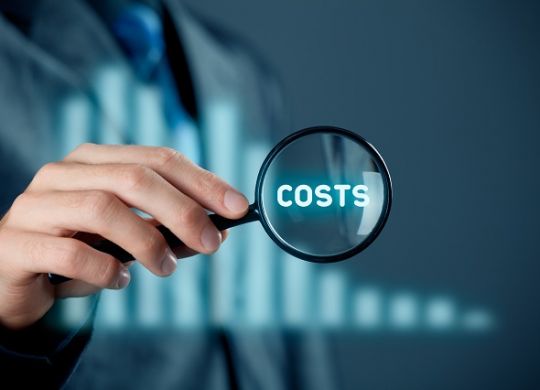 Focus on decrease (cut) costs concept. Businessman with magnifying glass enlarge word costs. Graph with decreasing costs on background.